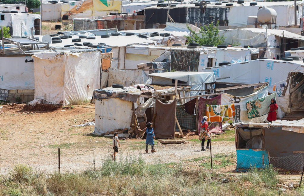 Syrian refugees stand near tents at a Syrian refugee camp in Marjayoun