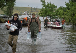 Ukrainian servicemen unload humanitarian aid for local residents after the Nova Kakhovka dam breached, in the flooded vill...