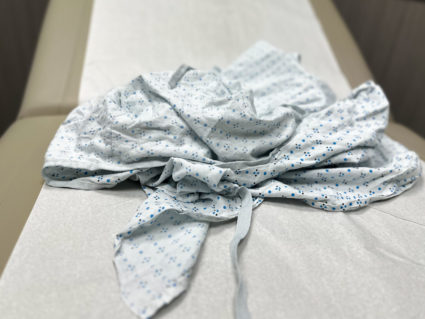 rumpled used patient gown on medical examination table