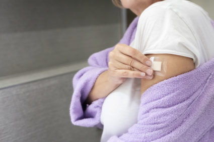 Woman using transdermal patch in the bathroom at home .