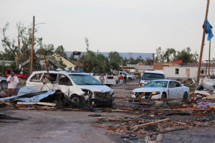 Debris and damaged vehicles cover a street after a tornado hit Perryton