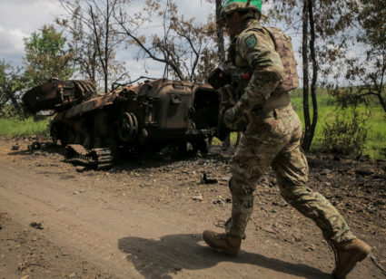 A Ukrainian service member runs near a destroyed Russian a BMP-2 infantry fighting vehicle in the newly liberated village ...
