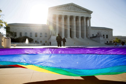 FILE PHOTO: Gay marriage supporters hold a gay rights flag in front of the U.S. Supreme Court before a hearing about gay m...
