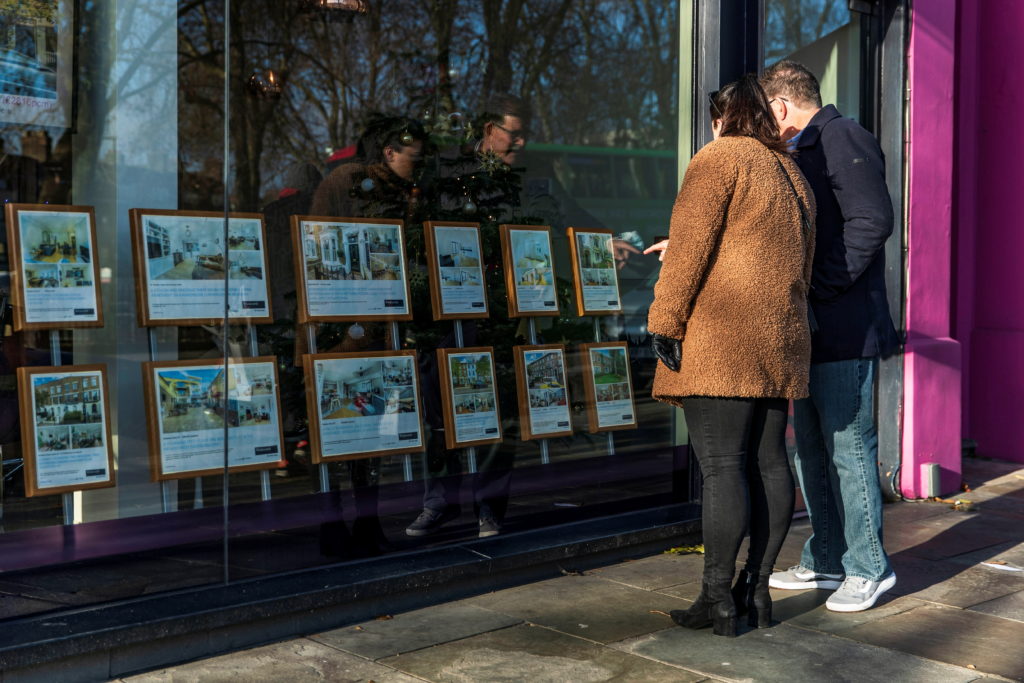 People look at properties on display in the window of Winkworth estate agents in Islington, London