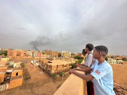 People watch as smoke rises during clashes between the army and the paramilitary Rapid Support Forces (RSF), in Omdurman