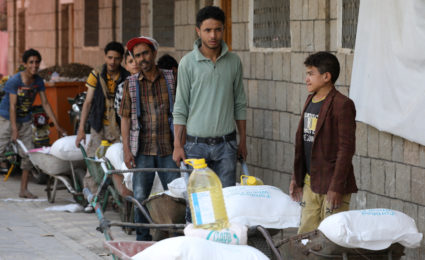 Workers ferry food for beneficiaries of the World Food Program at a distribution center, in Sanaa