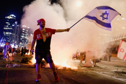 A protester holds an Israeli flag during a demonstration against Israeli Prime Minister Benjamin Netanyahu and his nationalist coalition government's judicial overhaul, in Tel Aviv, Israel July 20, 2023. Photo by Corinna Kern/REUTERS