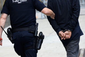 A police officer leads a person in handcuffs near the criminal court in Manhattan, New York City