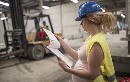 Pregnant worker woman in concrete factory looking note, looking at the work planning plan. Preparing labor
