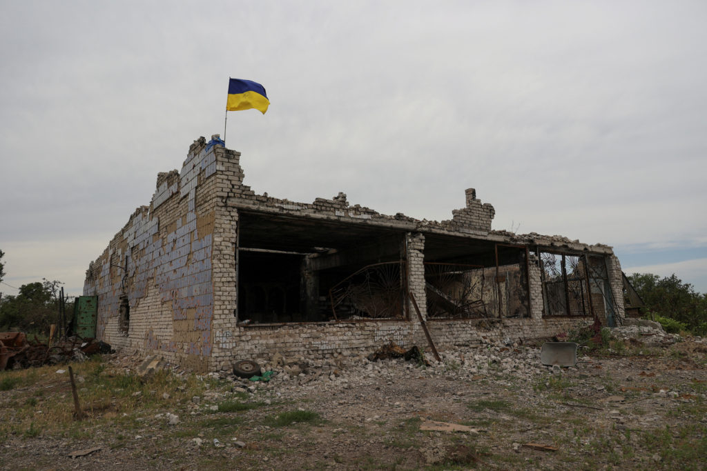 Ukrainian national flag installed atop of a destroyed building is seen in the village of Neskuchne