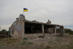 Ukrainian national flag installed atop of a destroyed building is seen in the village of Neskuchne