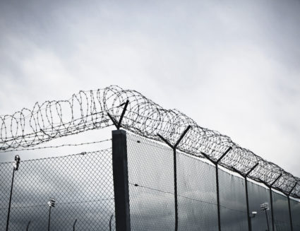 Chain link fence with barbed wire and razor wire.