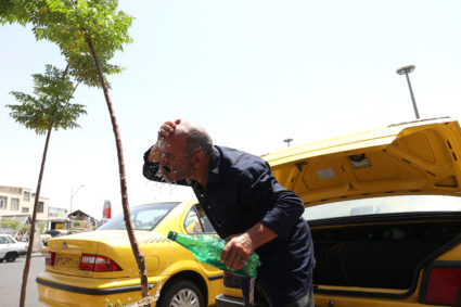 An Iranian taxi driver splashes water on himself to cool down during the heat surge in Tehran