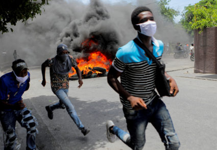 Men run next to burning tires during a protest demanding an end to gang violence, in Port-au-Prince, Haiti, August 14, 2023. Photo by Ralph Tedy Erol/REUTERS