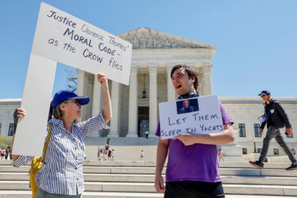 People hold signs decrying Justice Thomas in front of the Supreme Court Building in Washington