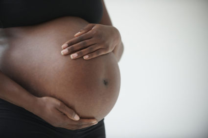 Midsection of pregnant Black woman holding belly
