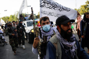 Taliban members ride a bike on the second anniversary of the fall of Kabul on a street near the U.S. embassy in Kabul