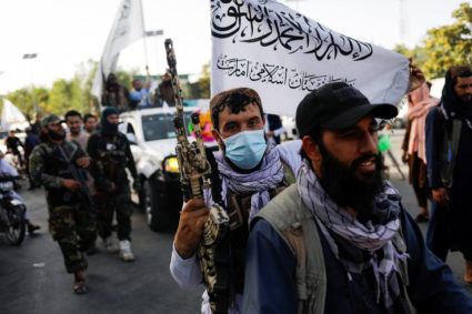 Taliban members ride a bike on the second anniversary of the fall of Kabul on a street near the U.S. embassy in Kabul