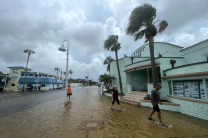 People wade through flood waters after Hurricane Idalia passed to the north, in St. Petersburg