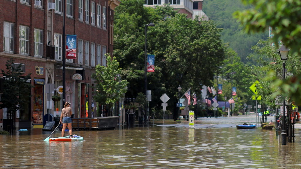 A person rows in a paddle board in a flooded area in Montpelier