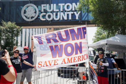 Supporters of former U.S. president Donald Trump hold a flag outside of the Lewis R. Slaton Courthouse, as Trump and 18 of his allies face a deadline to surrender to the jail in the criminal case brought by Fulton County District Attorney Fani Willis accusing him and his associates of trying to reverse his 2020 election loss in Georgia, in Atlanta, Georgia, U.S., August 25, 2023. Photo by Megan Varner/REUTERS