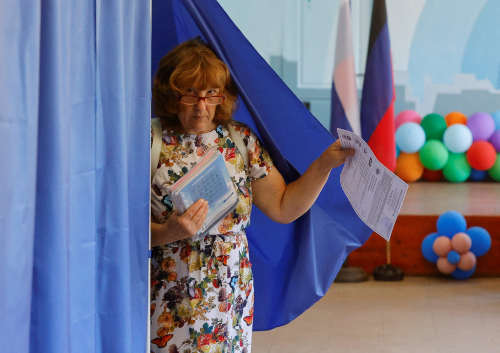 A woman walks out of a voting booth at a polling station during local elections held by the Russian-installed authorities ...