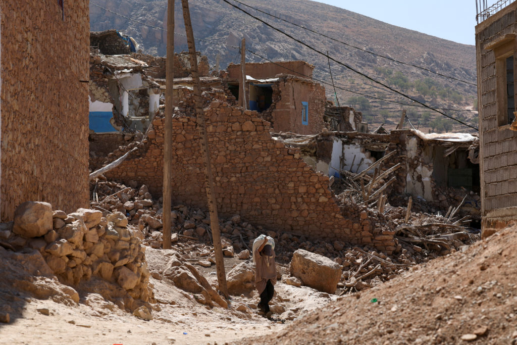 A man carries a heavy bag on his back following a deadly earthquake in Douzrou
