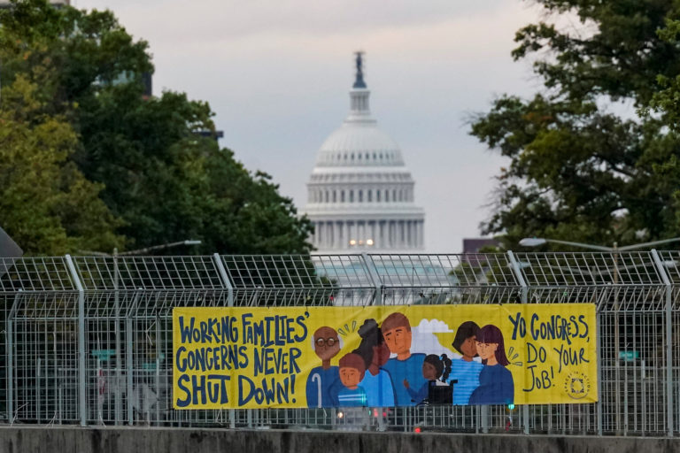 A view of a working families poster as the U.S. Capitol is seen in the background, as the deadline to avert a partial gove...