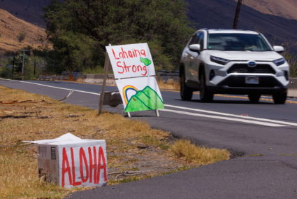 Local residents put up signs along the highway entering the fire ravaged town of Lahaina