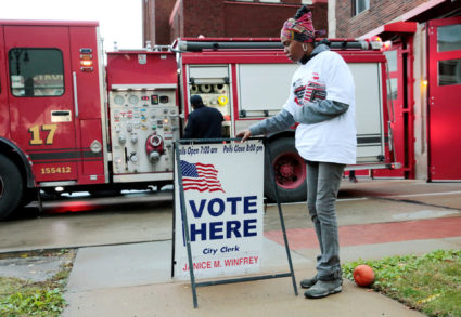 Campaign worker Kamisthial Jones adjusts a Vote Here sign outside a voting place for the midterm election in Detroit