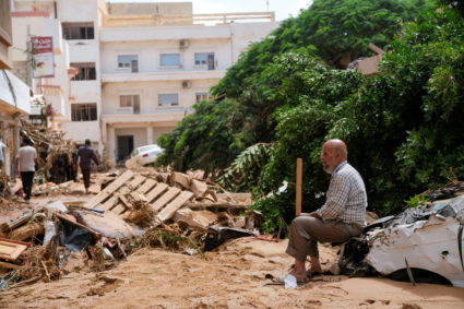 A man sits on a damaged car, after a powerful storm and heavy rainfall hit Libya, in Derna