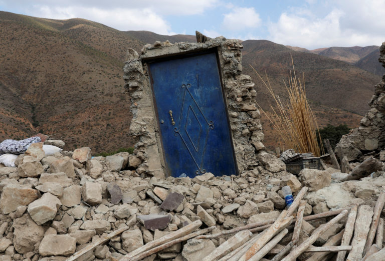 A blue door is seen surrounded by rubble in the devastated village of Adouz