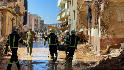 Members of the rescue teams from the Egyptian army carry a dead body as they walk in the mud between the destroyed buildin...