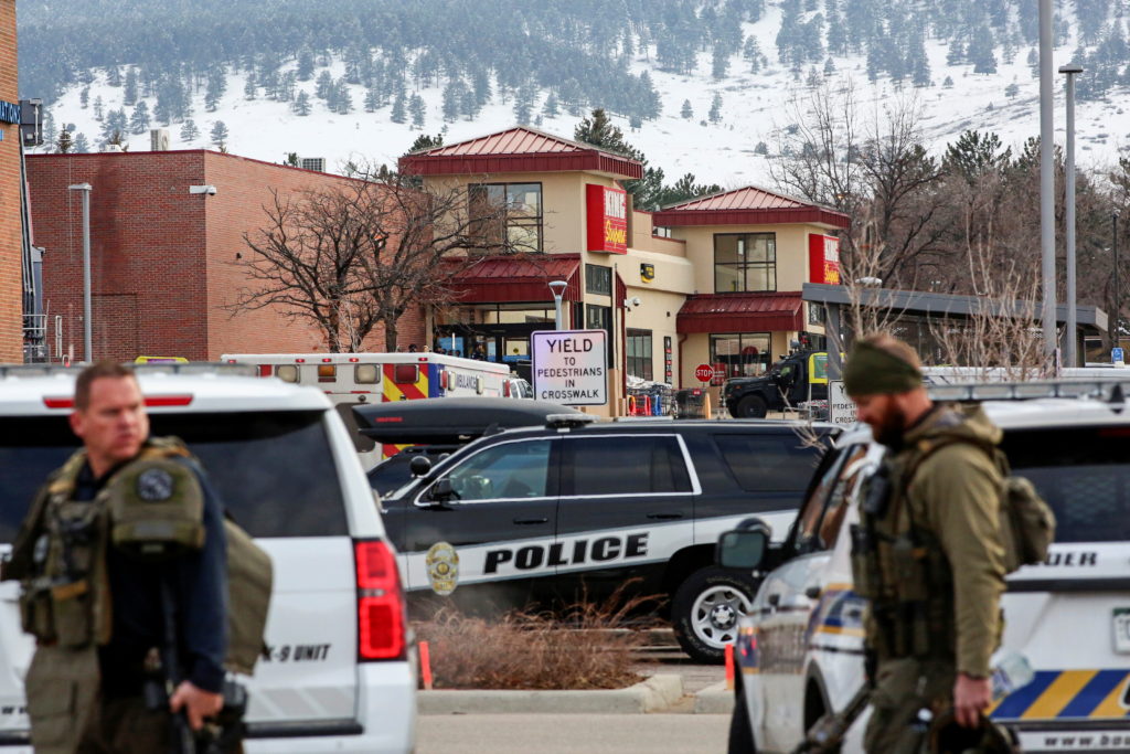 Law enforcement officers stand at the perimeter of a shooting site at a King Soopers grocery store in Boulder