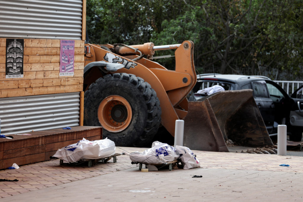 The dead bodies of two people lay on stretchers in a residential area following a mass infiltration by Hamas gunmen from t...