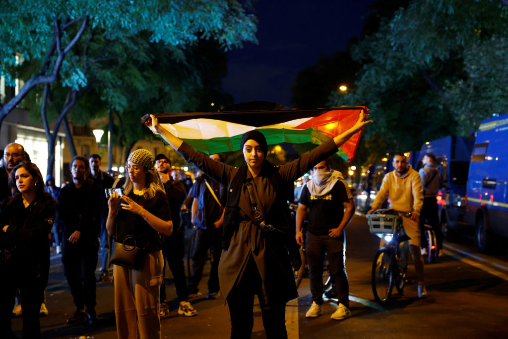 A woman holds a Palestinian flag during an unauthorized demonstration in support of Palestinians, as part of the ongoing conflict between Israel and the Palestinian Islamist group Hamas, at the Place de la Republique in Paris as French Interior Minister Gerald Darmanin ordered the systematic banning of pro-Palestinian demonstrations and the arrest of participants within France, October 12, 2023. The slogan on the statue reads "Free Palestine." Photo by Sarah Meyssonnier/REUTERS