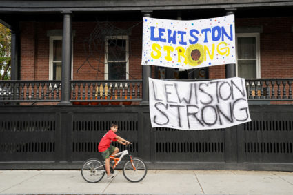 A boy cycles past "Lewiston strong" banners, as the search for the suspect in the deadly mass shootings continues, in Lewiston, Maine, U.S. October 27, 2023. Photo by Kevin Lamarque/REUTERS