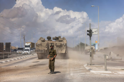 Israeli officer stands behind Israeli military vehicles near the border with the Gaza Strip
