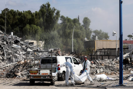 Israeli rescue workers work to remove dead bodies from near a destroyed police station that was the site of a battle follo...
