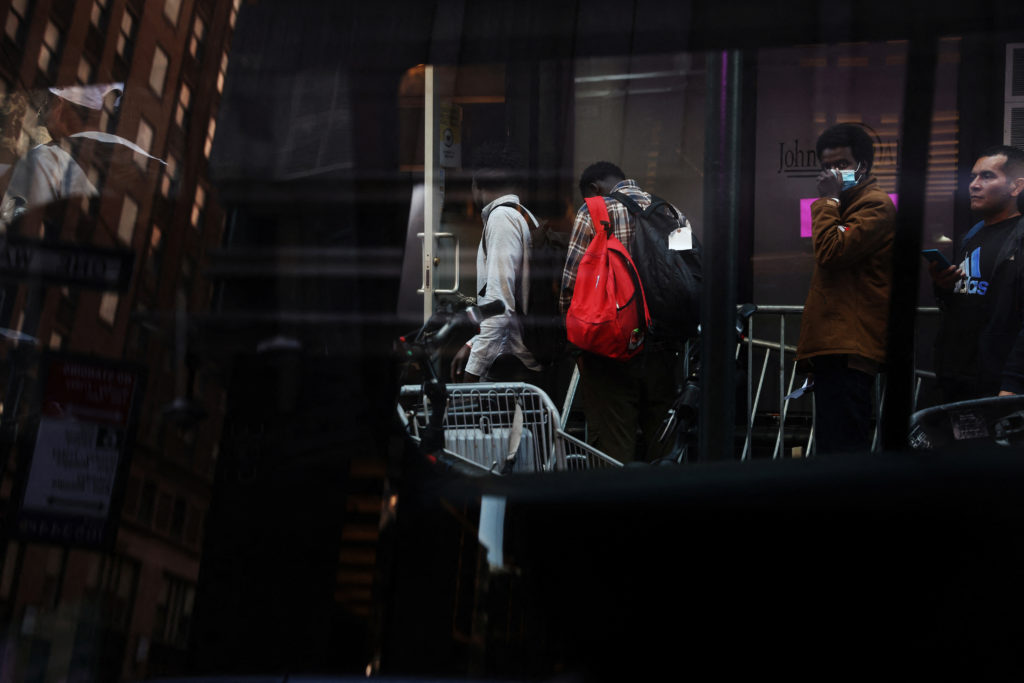 Migrant men wait in line outside the Roosevelt Hotel, which has acted as a makeshift shelter for arriving migrants since M...