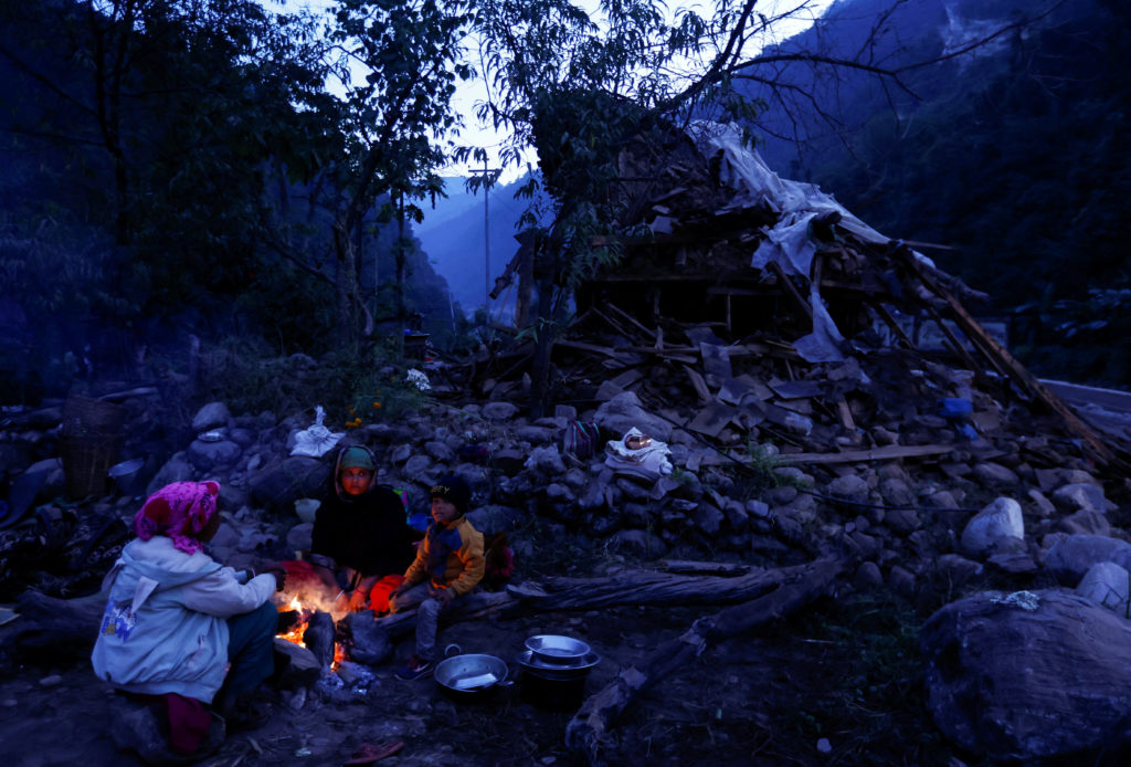 A family sits next to the fire to keep themselves warm early in the morning after spending the night out in the open after...