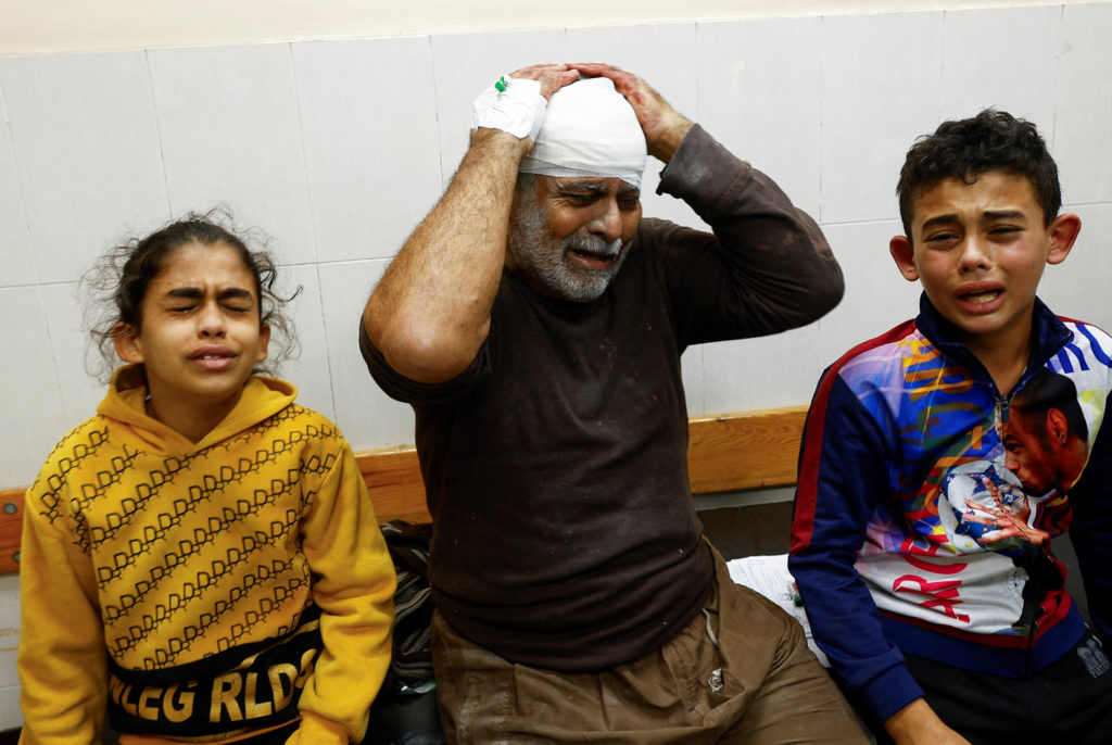 A Palestinian man wounded in an Israeli strike reacts next to children at Nasser hospital, amid the ongoing conflict betwe...