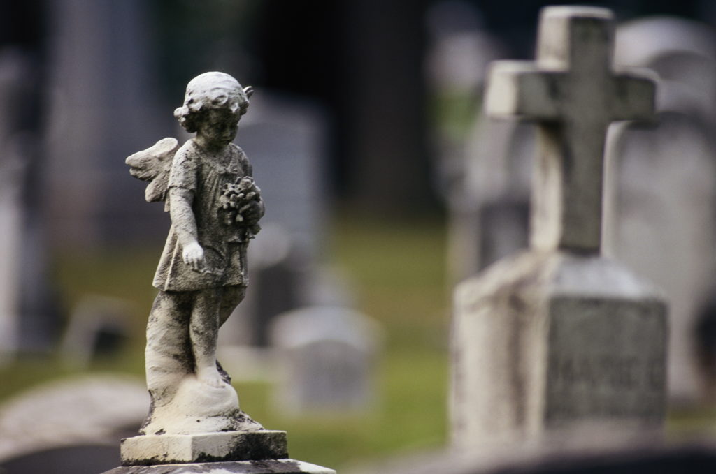Gravestones and statues in cemetery, close-up