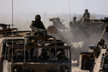Israeli soldiers ride military vehicles near the Israeli side of the border between Israel and the Gaza Strip
