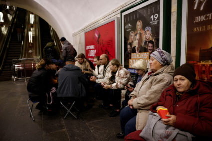 People sit in a metro station to shelter from an air raid in Kyiv