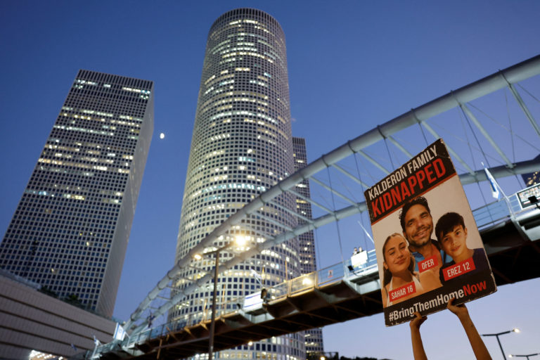 Israeli youth prepare an art installation of teddy bears with pictures of hostages, in Tel Aviv