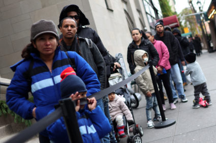 Recently arrived migrant families and others stand in line for a free meal in Manhattan in New York