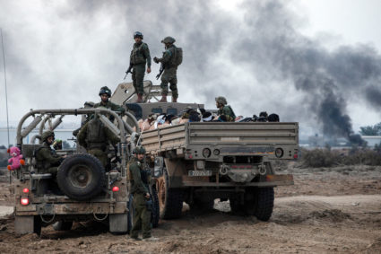 Israeli soldiers stand by a truck with Palestinian detainees on it amid the ongoing conflict between Israel and the Palest...
