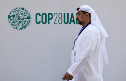A delegate walks past a logo of the COP28 climate summit in Dubai