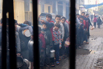 Palestinian children queue to receive food cooked by a charity kitchen, amid shortages in food supplies, as the conflict between Israel and Hamas continues, in Rafah in the southern Gaza Strip December 14, 2023. Photo by Saleh Salem/REUTERS